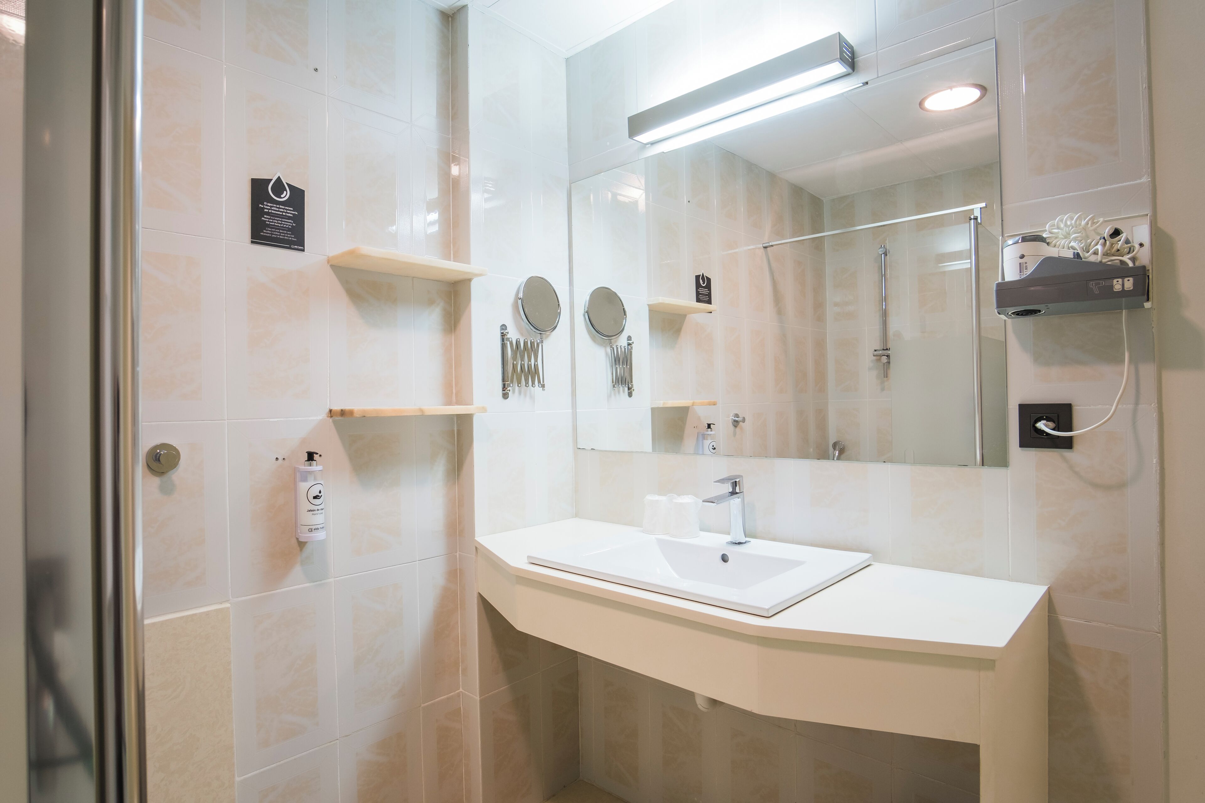 A modern bathroom with a white sink, mirror, and glass shower enclosure.