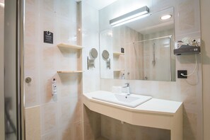 A modern bathroom with a white sink, mirror, and glass shower enclosure.