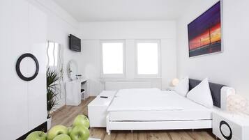 Ein modernes Schlafzimmer mit einem weißen Bett, Nachttischen, einem Fernseher und einem großen Fenster.