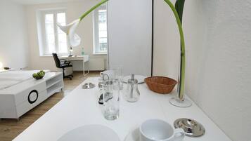 Une chambre à coucher moderne et minimaliste, avec un lit blanc, un bureau et une grande fenêtre.