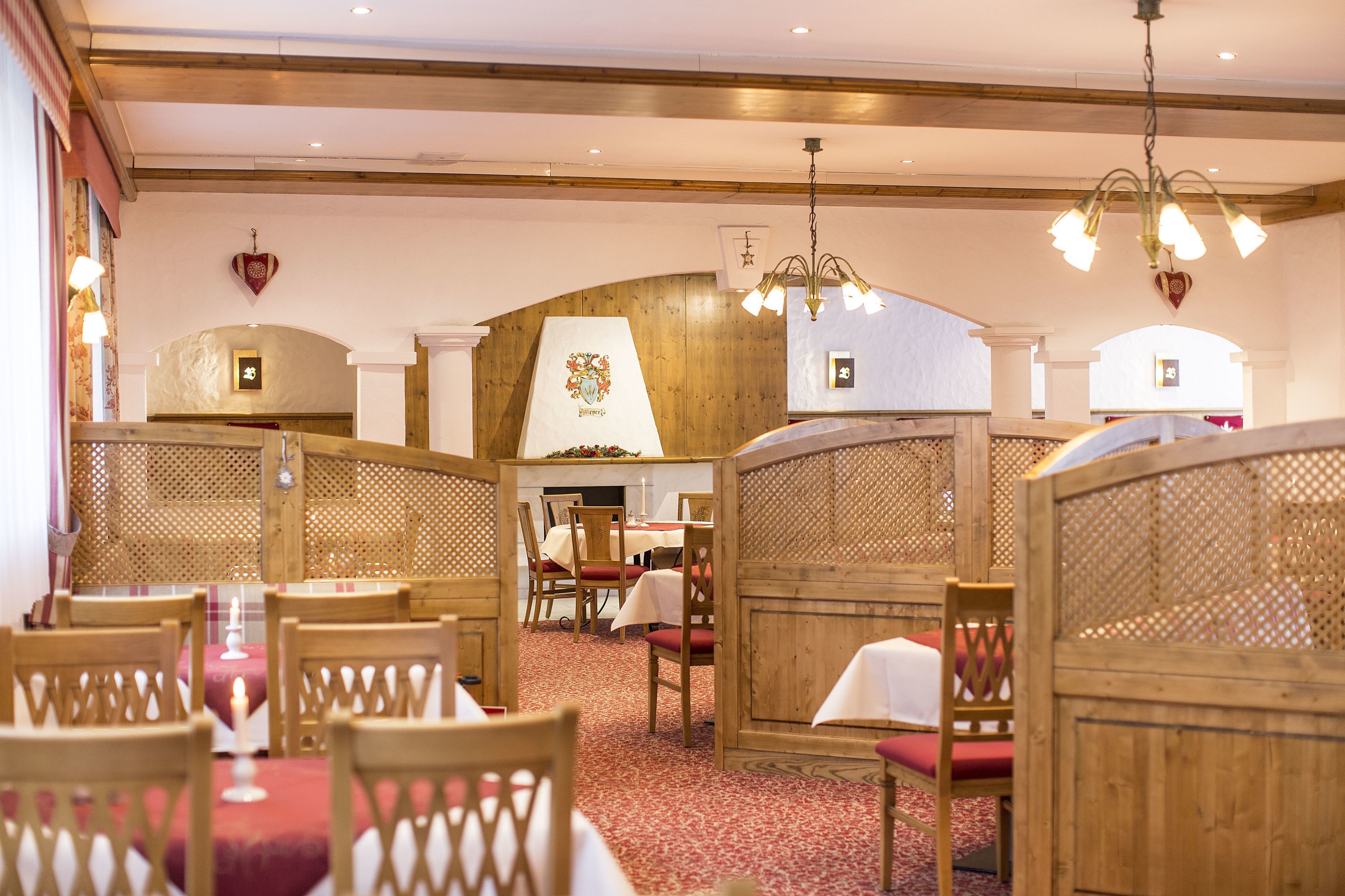 Ein Restaurant mit Holztischen, rotem Teppichboden und einer Kristallleuchter.