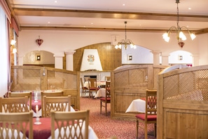 A restaurant with wooden furniture, red carpet flooring, and a chandelier. - Wellnesshotel Bürgerstuben (Willingen)