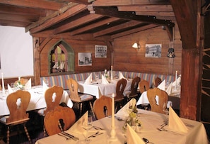 A dining area with wooden tables and chairs, white tablecloths, and candles. - Wellnesshotel Bürgerstuben (Willingen)