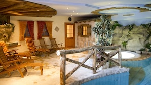 A spa area with wooden chairs, a stone wall, a wooden fence, and a large bathtub.