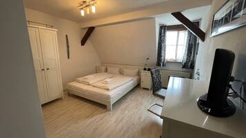 Een slaapkamer met een bed, nachtkastjes, een bureau, een stoel, een kledingkast en een plafondlamp.