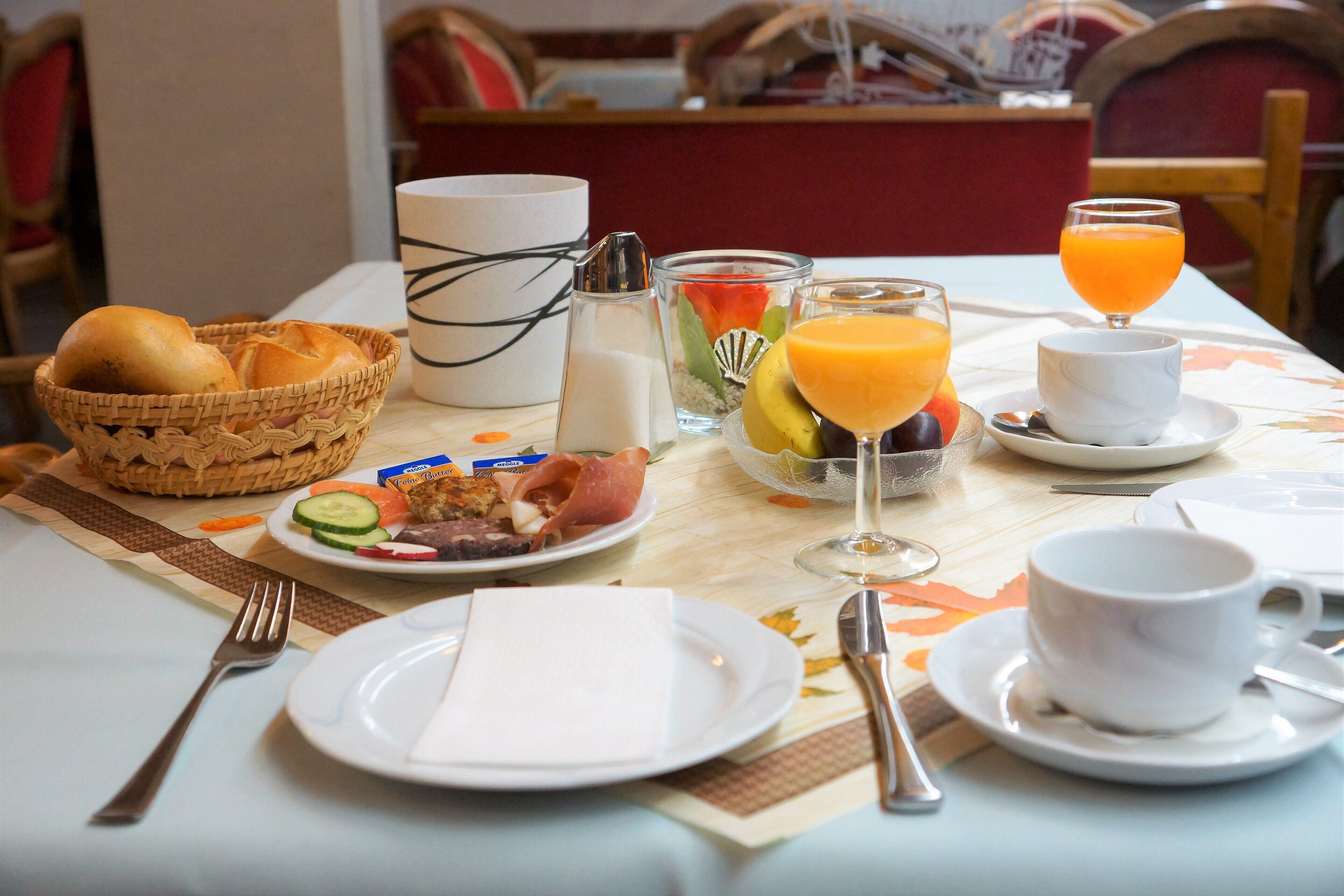 Mesa de café da manhã com pão, frutas e suco.