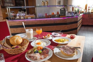 A breakfast buffet with various dishes, including eggs, meats, and a drink.