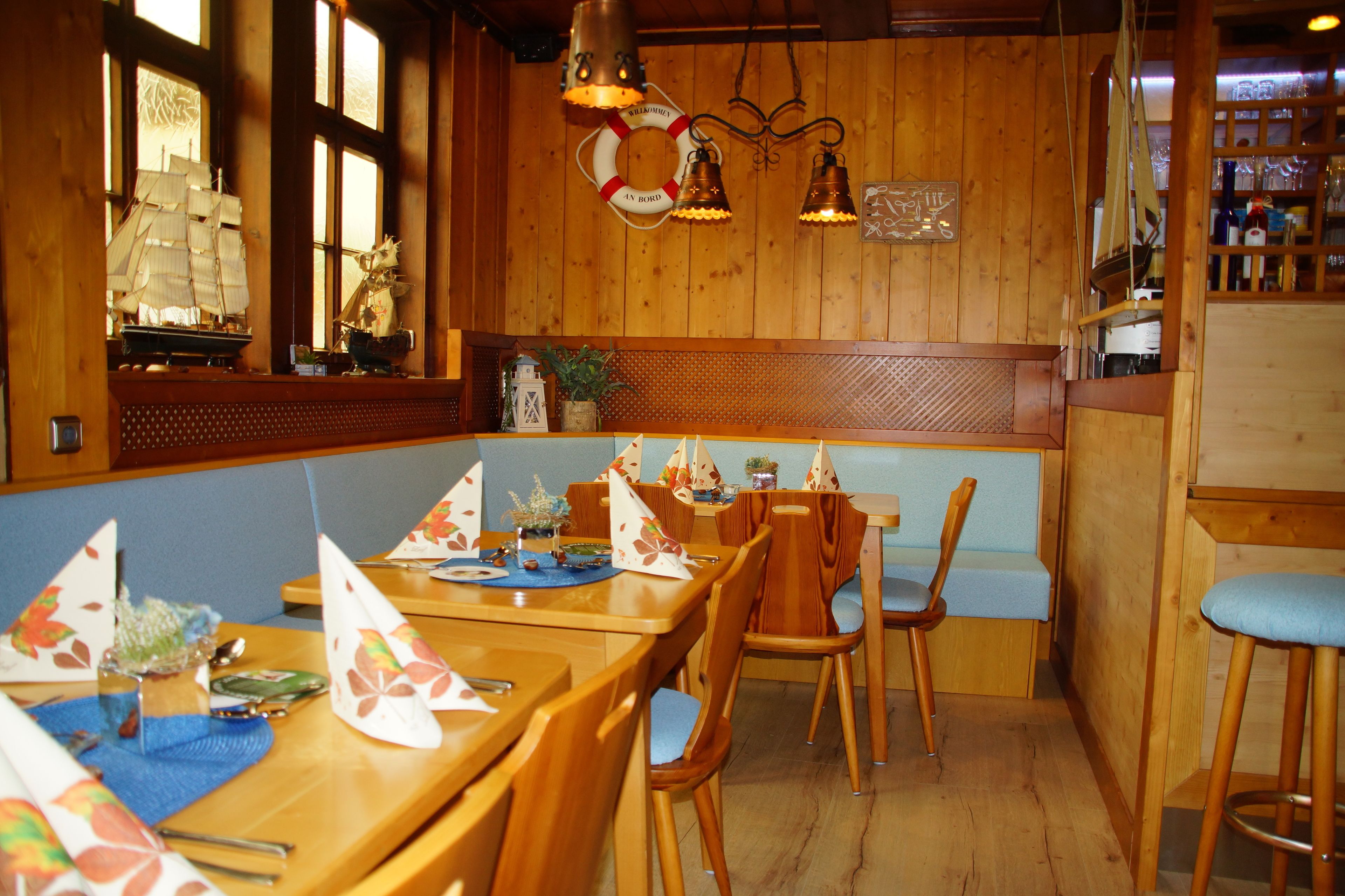 Een houten interieur met een lange tafel, stoelen en een bank.