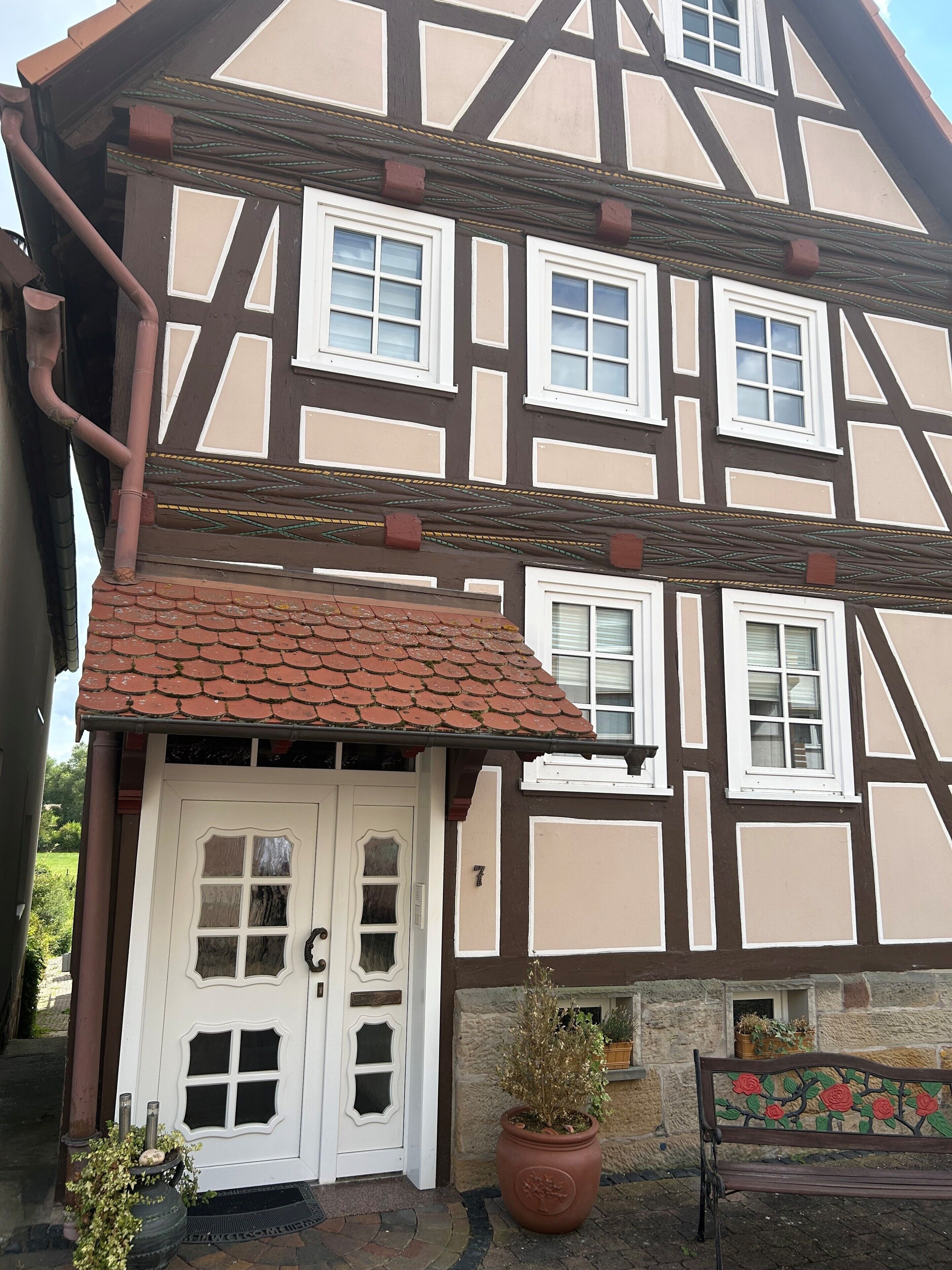 Una casa tradicional con entramado de madera, una puerta blanca y varias ventanas.