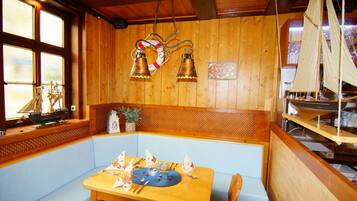 A wooden interior with a table set for dining, a bench, and a decorative sailboat model.