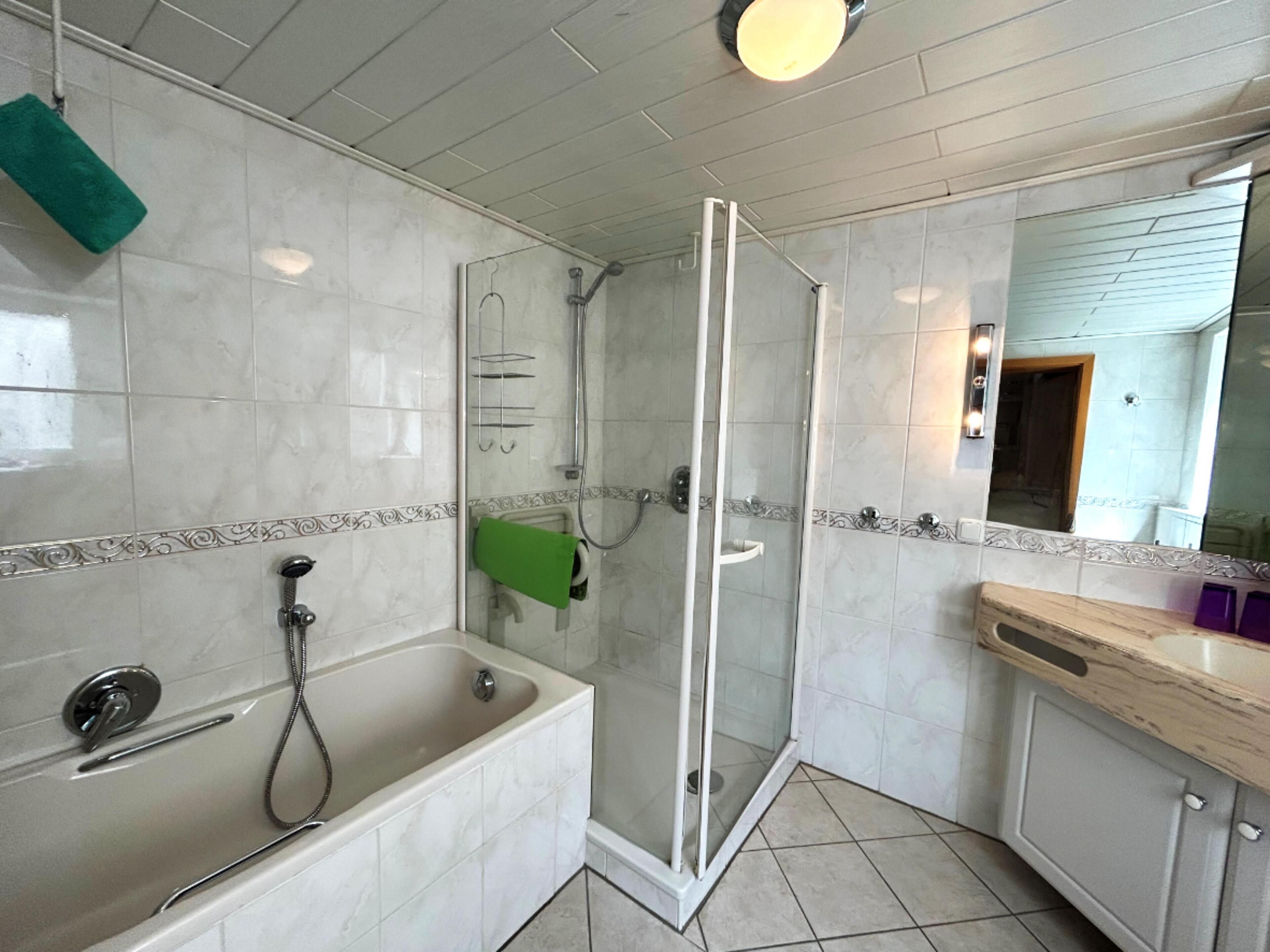 A modern bathroom with a bathtub, shower, and glass-enclosed shower stall.