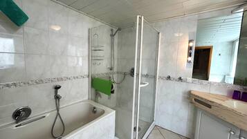 A modern bathroom with a bathtub, shower, and glass-enclosed shower stall.