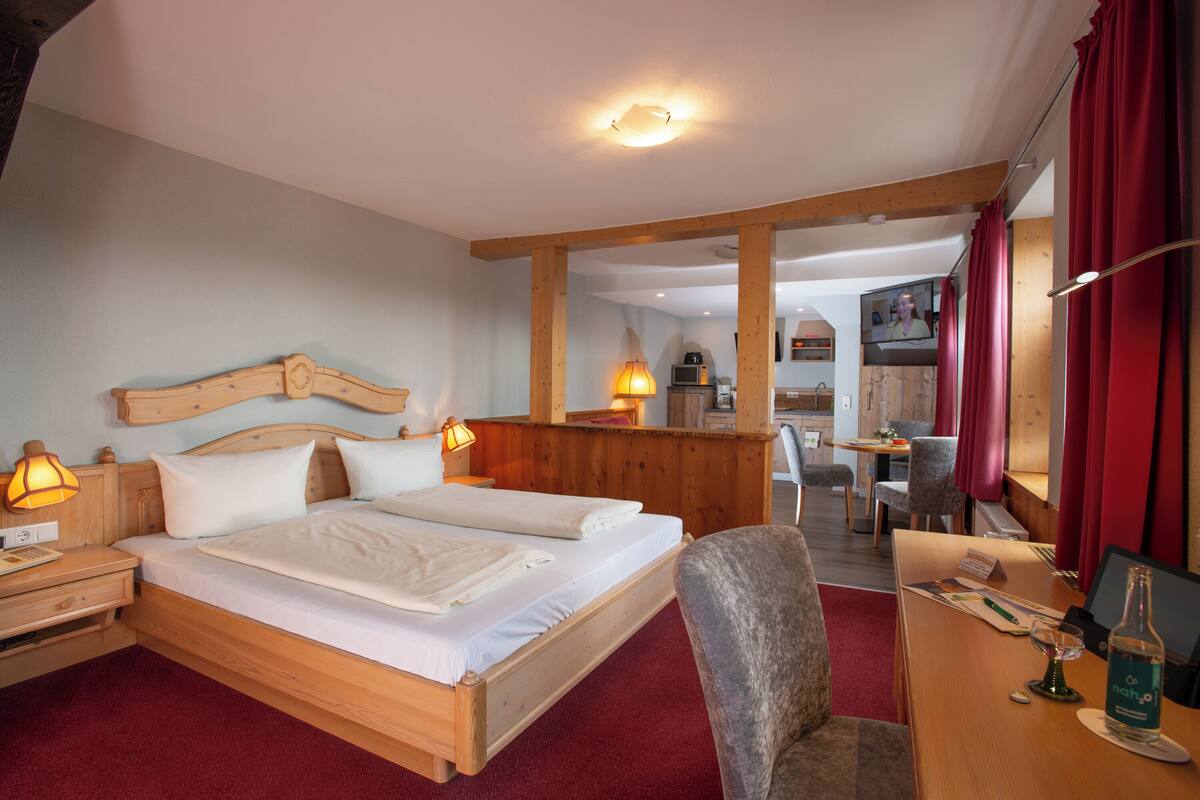 A hotel room with a wooden bed, a desk with a computer, and a chair.