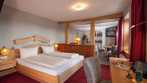 Hotellihuone, jossa on puinen sänky, työpöytä tietokoneella ja tuoli.