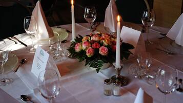 Una mesa dispuesta para una comida, con velas, copas de vino y un centro de mesa floral.