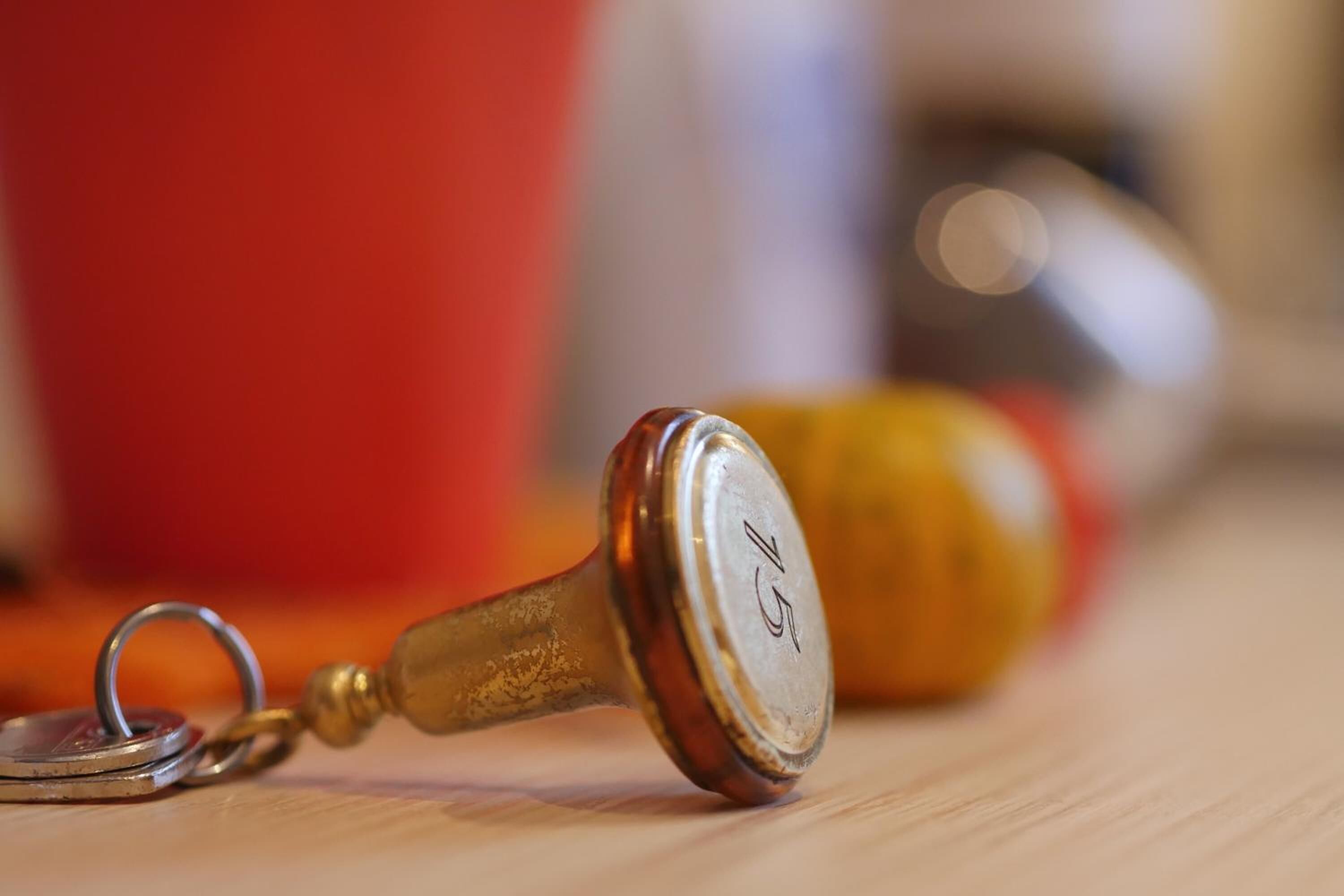 A close-up of a vintage keychain with a metal ring and a wooden handle.