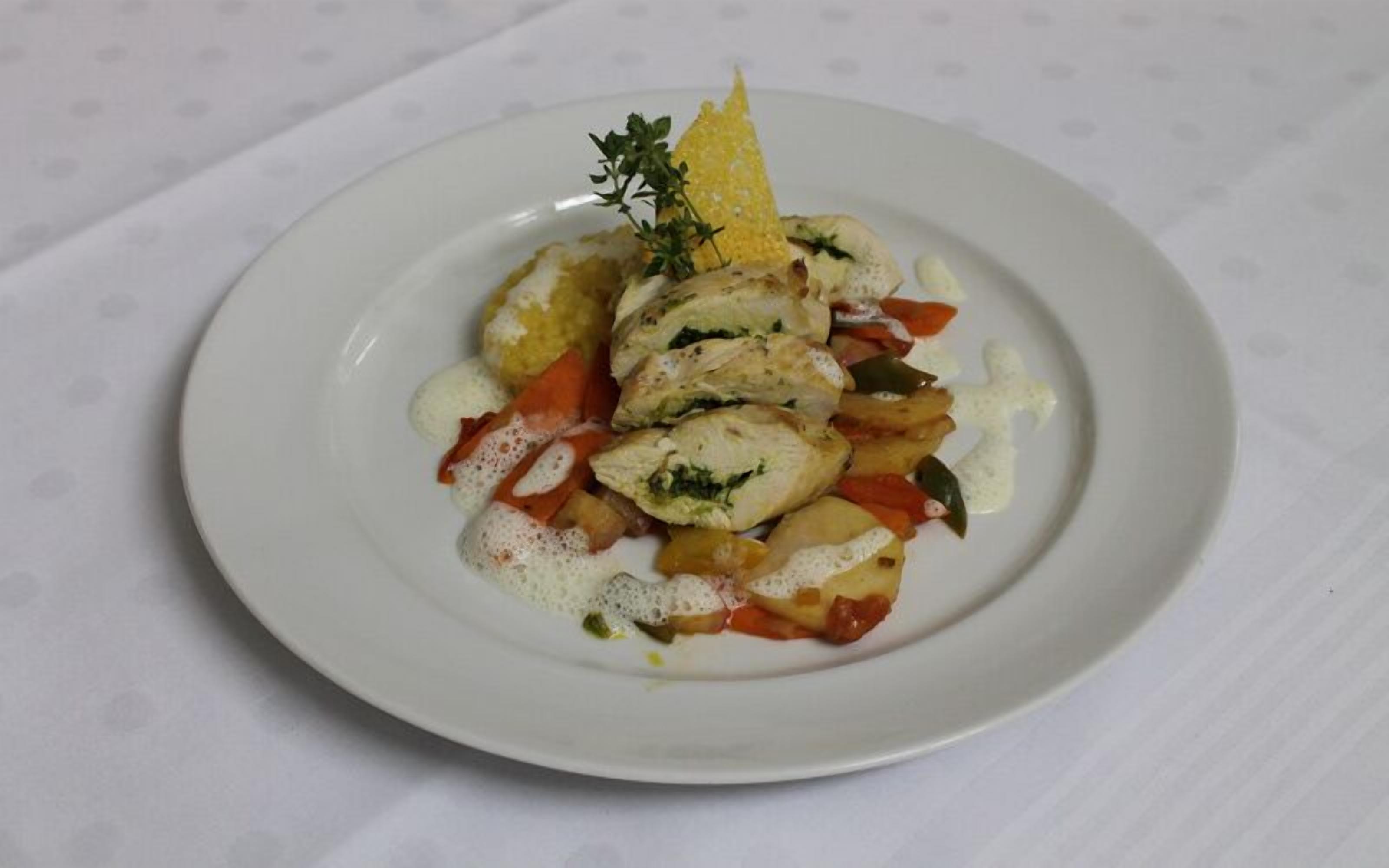 A white plate with a dish of stuffed vegetables and a sprig of thyme.