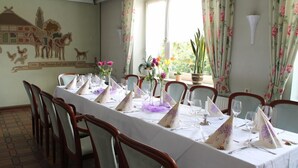 A dining table set for a meal with chairs, a floral curtain, and a wall mural. - Gasthof Vossbur (Toppenstedt)