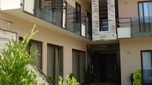 Un edificio residencial de varios pisos con balcones, fachada de piedra y zona de piscina.