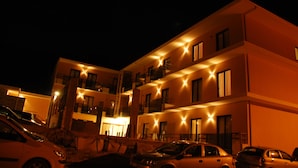 Un hotel de varios pisos con balcones y un estacionamiento.