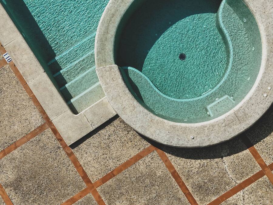 Una piscina circular con borde de azulejos, rodeada de un área con diseño de guijarros.