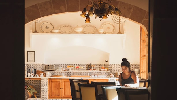A kitchen with a tiled backsplash, wooden cabinets, and a hanging light fixture. - Finca Can Estades (Calvia)