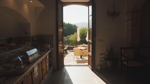 An interior corridor leading to an outdoor patio area with a view of trees and hills. - Finca Can Estades (Calvia)