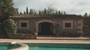 A stone building with a tiled roof, a pool, and outdoor seating. - Finca Can Estades (Calvia)