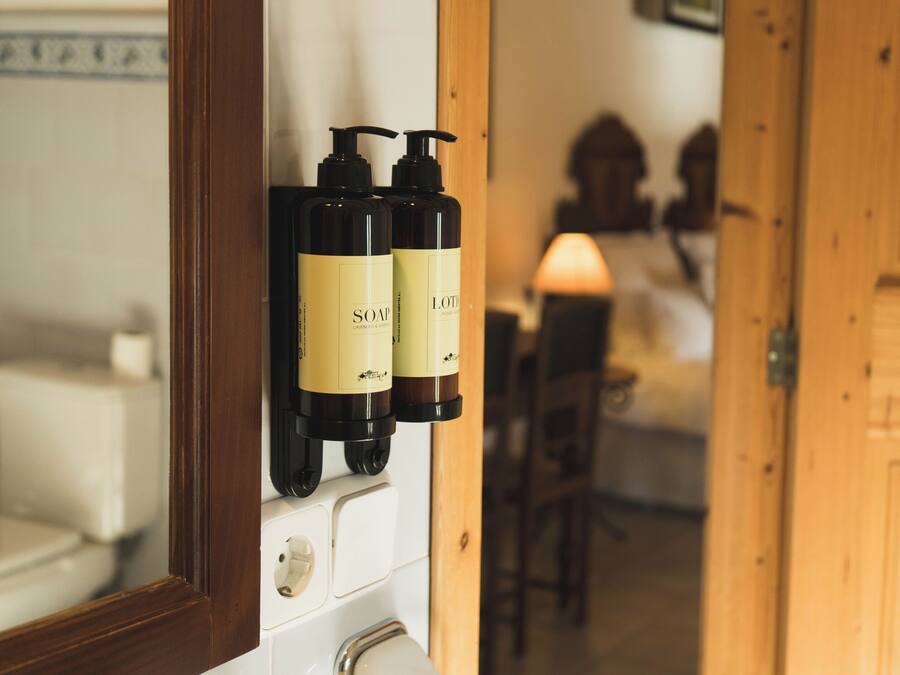 Un baño con dos botellas negras etiquetadas "SOAP" y "LOTUS" sobre una pared blanca.