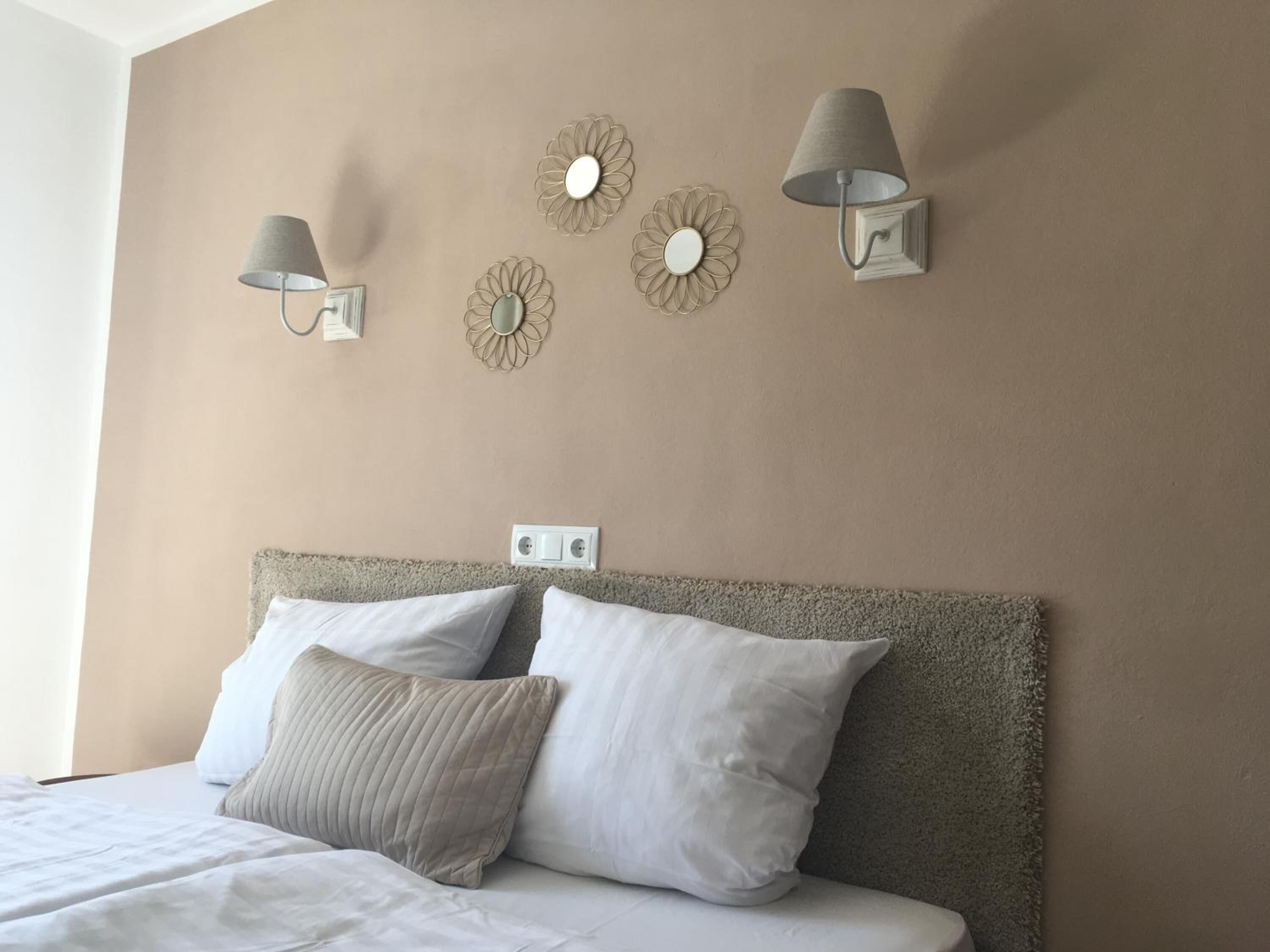 Un dormitorio con una cama, dos lámparas fijadas a la pared y decoración mural.