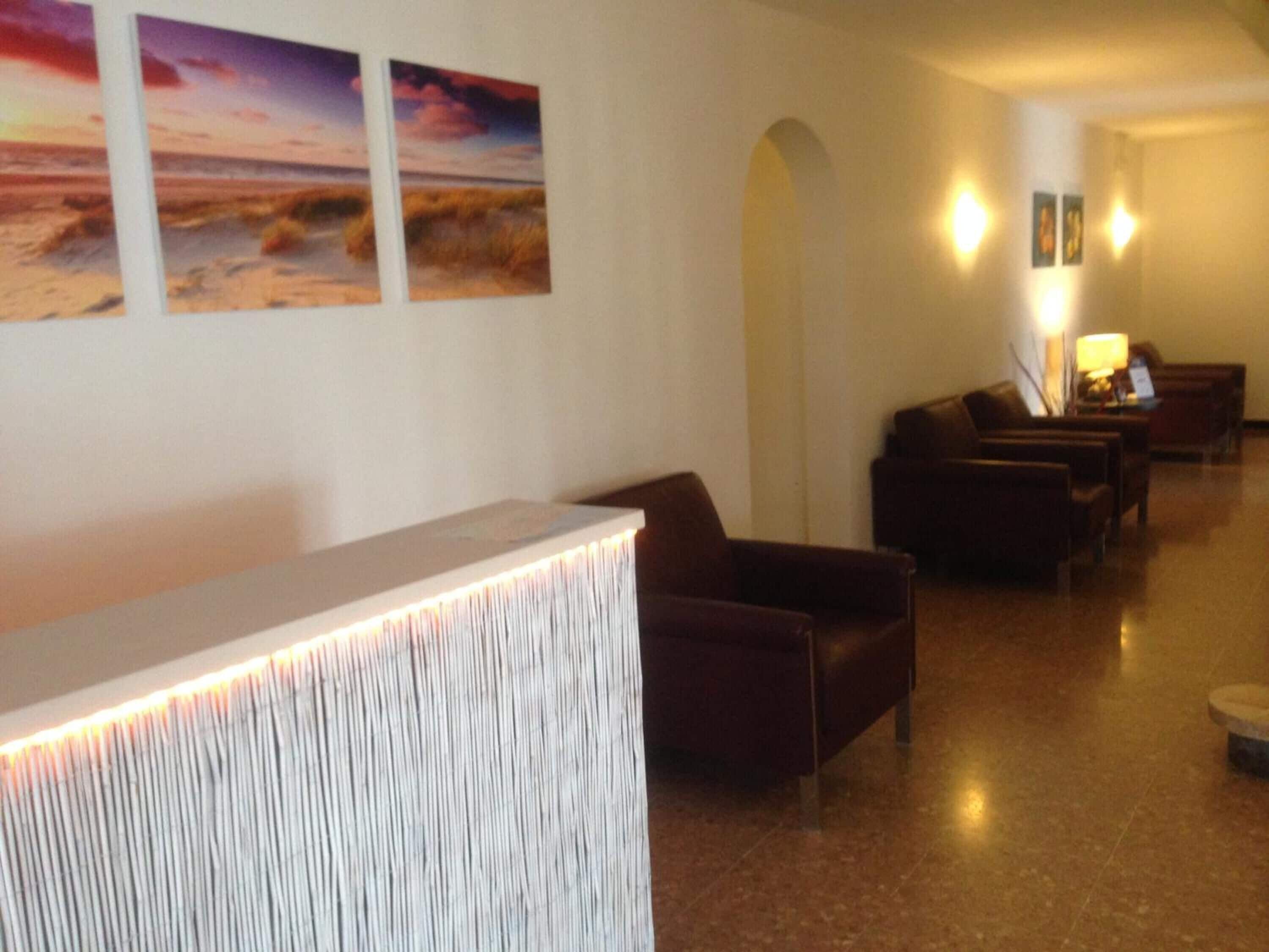 Un espace d’accueil comprenant un comptoir de réception, un coin salon et des œuvres d’art accrochées au mur.
