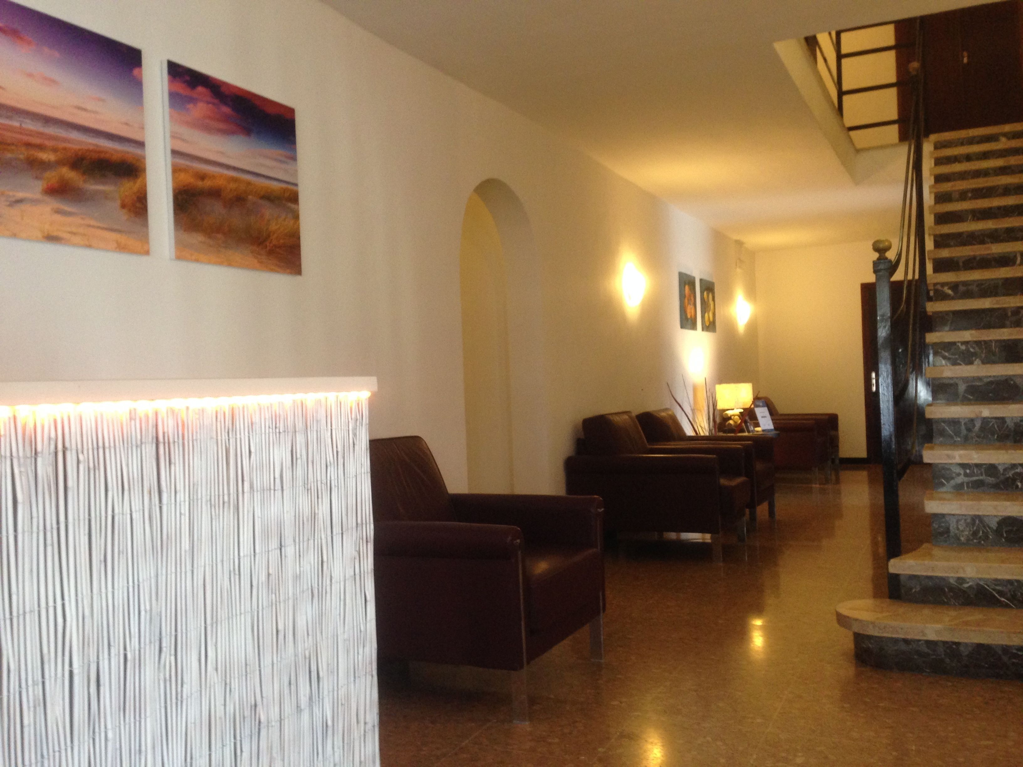 A lobby with a reception desk, seating area, and a staircase.