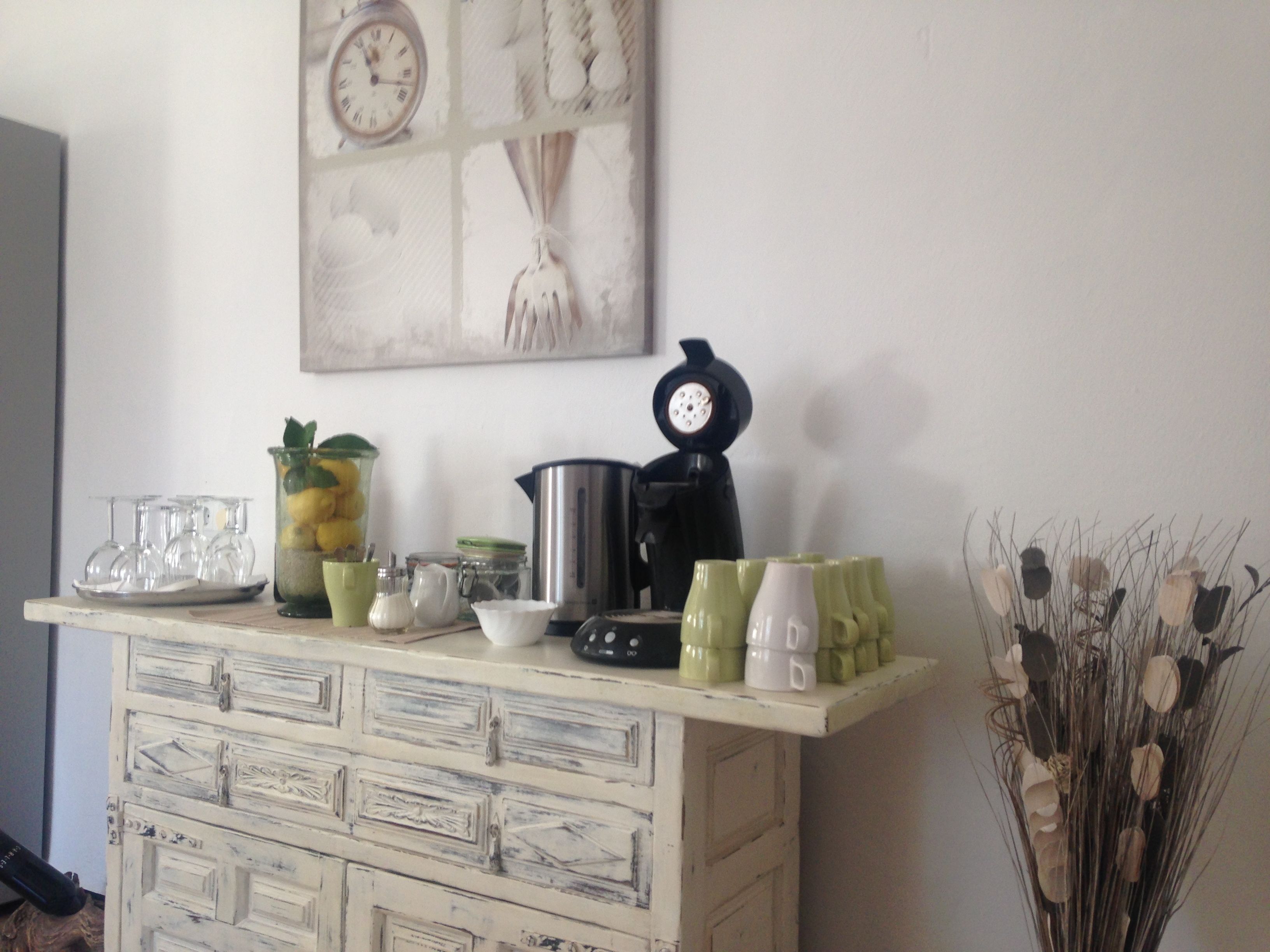 A kitchen counter with various items including a coffee maker, a kettle, and a decorative clock.