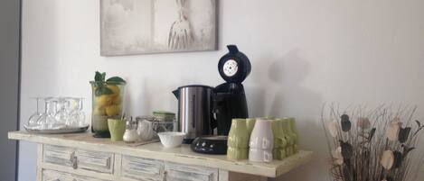 A kitchen counter with various items including a coffee maker, a kettle, and a decorative clock.