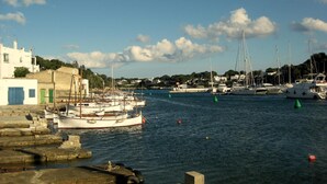 Un port de plaisance avec des bateaux amarrés, un ciel dégagé et des bâtiments en arrière-plan.