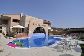 A swimming pool with a stone building in the background. - Astir Notos (Thasos)