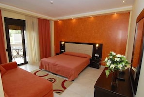 A hotel room with two beds, a desk, a chair, and a large window. - Astir Notos (Thasos)