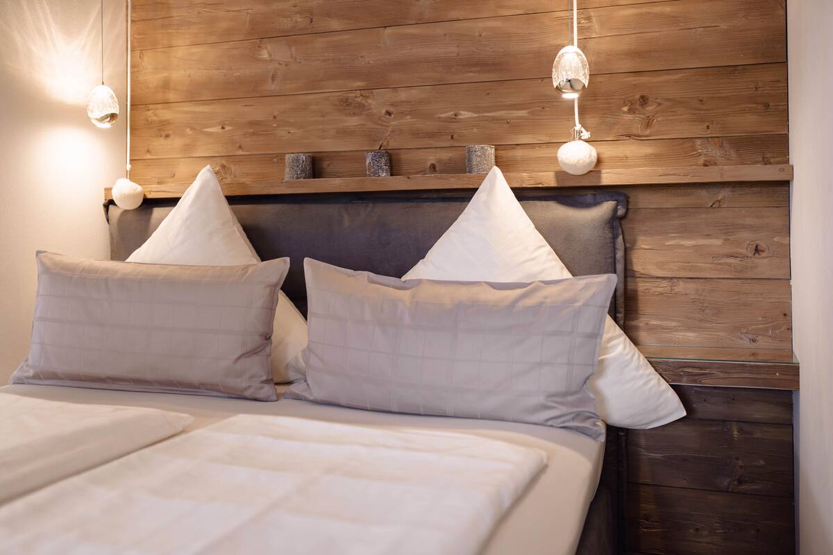 A bed with a wooden headboard, two pillows, and a light fixture.