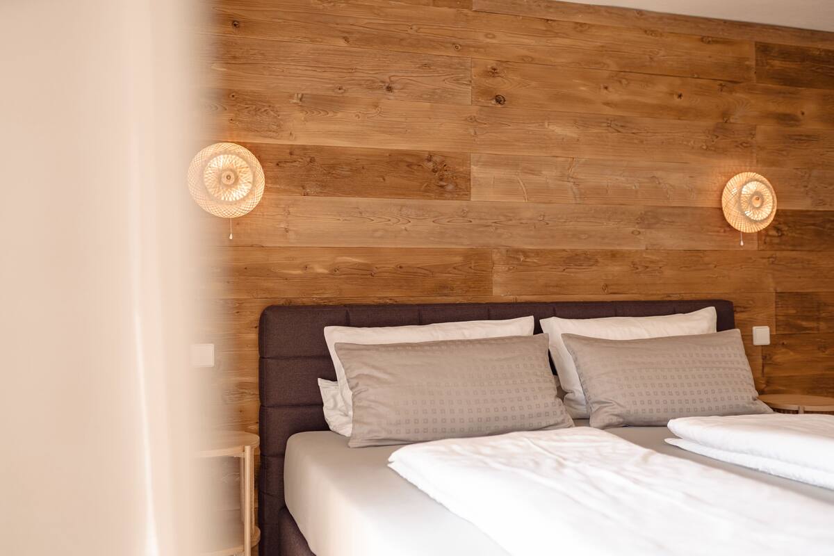 A bedroom with a wooden headboard, two bedside lamps, and a bed with white linens.