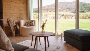 Una habitación acogedora con detalles de madera, una mesa redonda con un florero, un sillón mullido y un sofá.