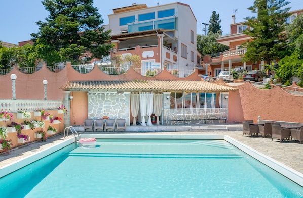 A swimming pool with a sun terrace, stone walls, and outdoor seating.