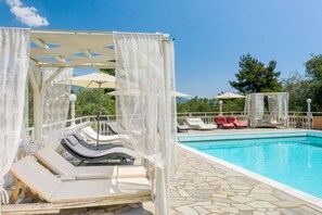 A poolside area with lounge chairs and umbrellas. - Victoria Hill (Corfu)