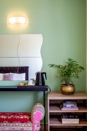 A room with a bed, bedside table, lamp, potted plant, and a bookshelf with books. - Victoria Hill (Corfu)