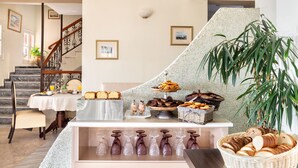 Un buffet de petit-déjeuner proposant diverses pâtisseries et du pain, un escalier et une grande plante.