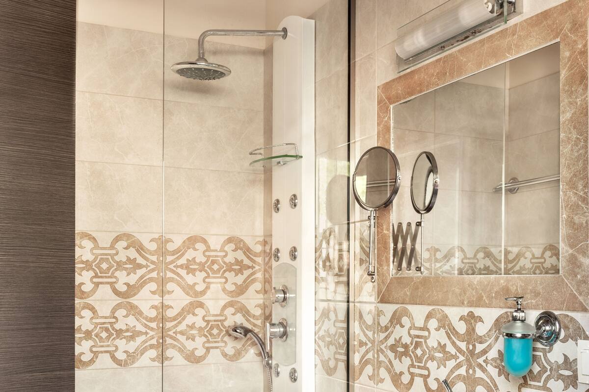 A bathroom with a shower, a sink, a mirror, and a towel.