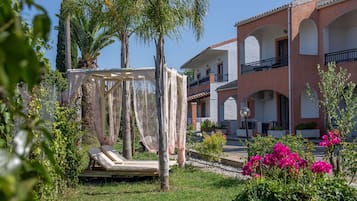 Un jardin avec un hamac, des palmiers et un bâtiment doté de balcons.