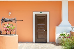 A building entrance with a brown door, a metal gate, and potted flowers. - Victoria Hill (Corfu)