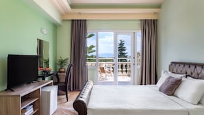 A bedroom with a bed, a television, a desk, and a view of the outdoors. - Victoria Hill (Corfu)