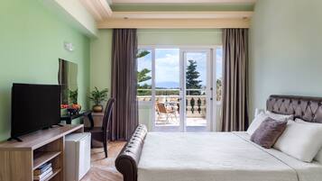A bedroom with a bed, a television, a desk, and a view of the outdoors.