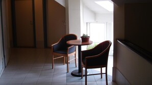 Een kleine, goed verlichte kamer met twee stoelen en een tafel, een keukendeur en uitzicht op de omgeving.